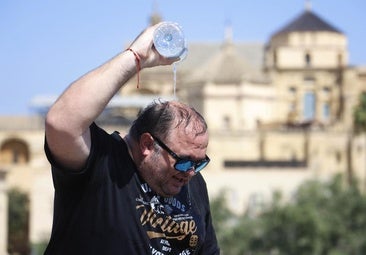 Un hombre se refresca con una botella de agua
